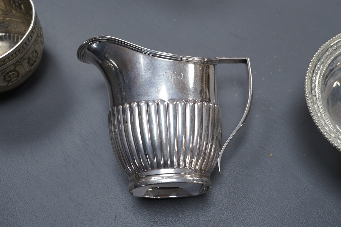 A George V demi-fluted silver cream jug, by William Hutton & Sons Ltd, Sheffield, 1922, height 98mm, together with a smaller silver ream jug, a small silver pedestal bowl and a late Victorian silver Anglo-Indian sugar bo